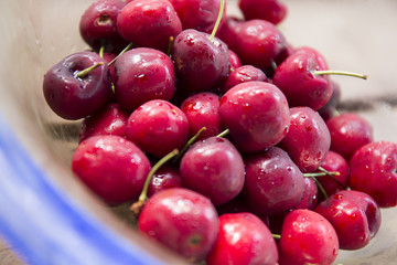 Ripe red cherries inside the transparency blue bowl on the table