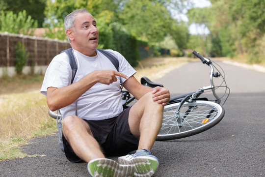 aching man after bicycle accident on the asphalt