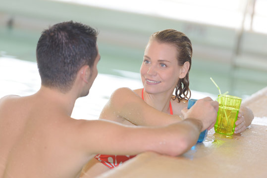 man and woman having a drink on the swimming pool