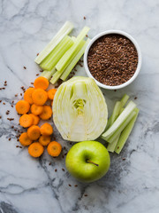 Ingredient for smoothie with fennel, apple, carrots, celery and flax seeds on marble table background