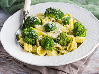 Orecchiette pasta with broccoli in white dish on wooden table. Easy recipe for lunch.