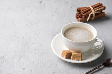 hite coffee Cup and saucer with milk foam and cane sugar on concrete background