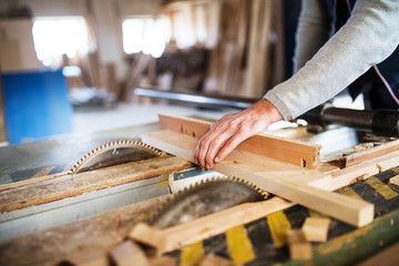 A man worker in the carpentry workshop, working with wood.