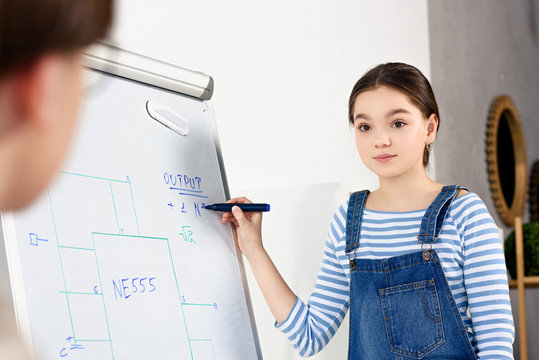 cropped image of female teenager pointing on flipchart to friend at home