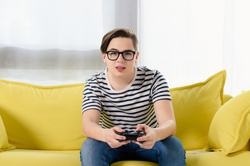 Fototapeta premium teen boy playing video game on sofa at home