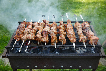 Shashlik or shashlyk preparing on a barbecue grill over charcoal. Grilled cubes of pork meat on...