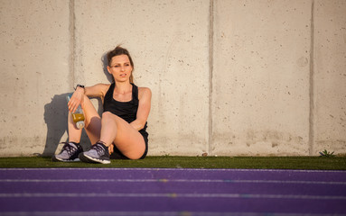 Fitness woman resting after training on stadium running track