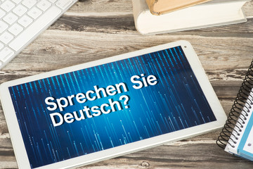 Schulheft, Schulbücher und ein Tablet PC zum Lernen von deutscher Sprache