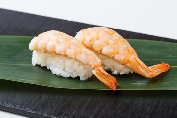 Nigiri sushi served on black stone slate, white background