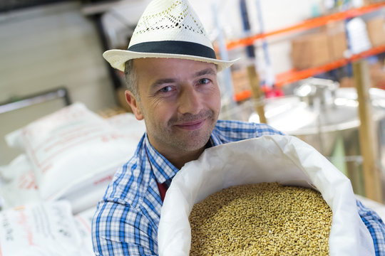 Man in hat holding sack of grains
