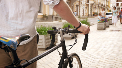 Closeup photo of man with retro bicycle walking on street