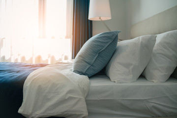 white and blue soft pillow on white bed sheet bedroom background with morning light