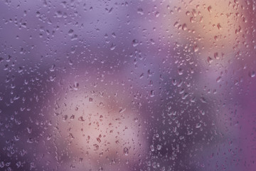 Fototapeta premium Abstract violet and orange background, texture of rain drops on glass. Raindrops on window, rainy weather.