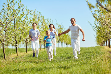 Happy family having fun walking in the garden in spring, summer. Mother, father and sons in nature.