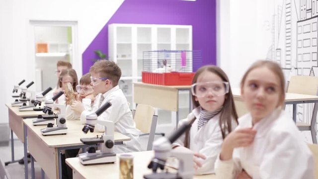 Elementary school biology, chemistry class. kids looking through microscope