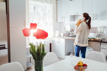 Woman cooking dinner in new kitchen and talking on the phone. Modern kitchen design.