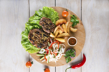 Grilled steak and vegetable salad on wooden rustic table.Top view.