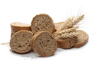 Loaf of integral bread with sesame, ears of wheat and slices isolated on white background