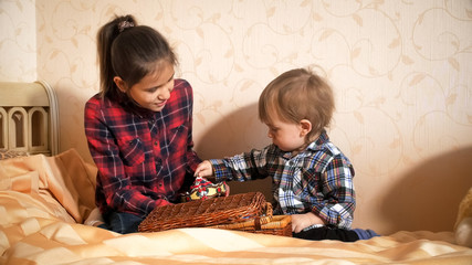 Teenage girl playing with toddler boy on bed at bedroom
