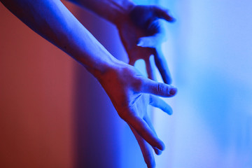 Human body parts hands wrists fingers in Neon fluorescence Fluorescent lights red blue background blurred
