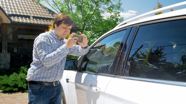 Young man making photos on smartphone of his car