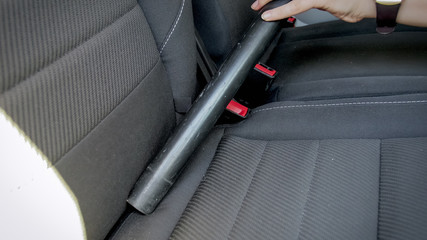 Closeup photo of female hand holding vacuum cleaner tube clening car seats