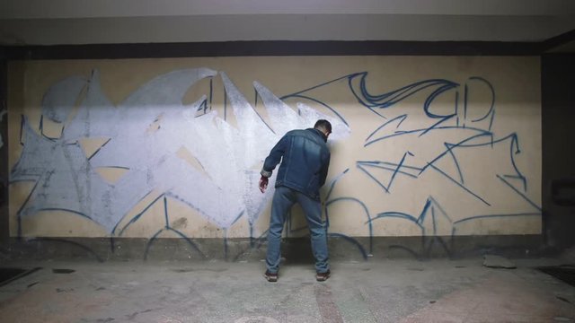 Graffiti artist painting on the wall in subway