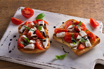 Caprese Bruschetta. Tomatoes, basil, mozzarella cheese with balsamic reduction drizzle on toast. Antipasto - starter dish