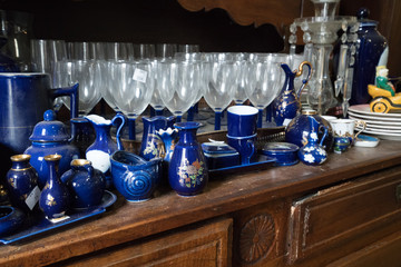 Glassware and blue  cups on a wooden buffet.