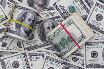 money roll against the background of hundred-dollar bills