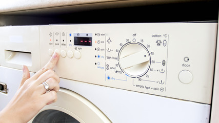 CLoseup photo of young woman setting program of washing machine