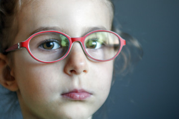 Smart little girl in red glasses close-up. Correction of vision in childhood. Treatment of amblyopia