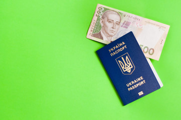 One blue biometric ukrainian foreign passport with gold color inscription and coat of arms on green background and banknote of five hundred hryvnias. Economic concept with copy space