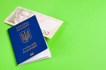 One blue biometric ukrainian foreign passport with gold color inscription and coat of arms on green background and banknote of five hundred hryvnias. Travel concept with copy space