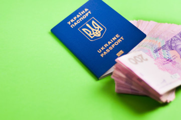 One blue biometric ukrainian foreign passport with gold color inscription and coat of arms on green background and lot of banknotes of two hundred hryvnias. Economic concept with copy space