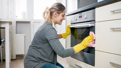 Beautiful smiling woman doung housework and cleaning kitchen