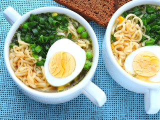 Noodle soup in a white bowl with egg and green onion