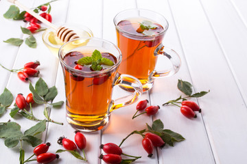 Healthy autumn  tea with dog roses, branch with berries on white  background.