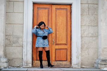 African american girl in jeans dress posed on streets of city. Black stylish model shoot.
