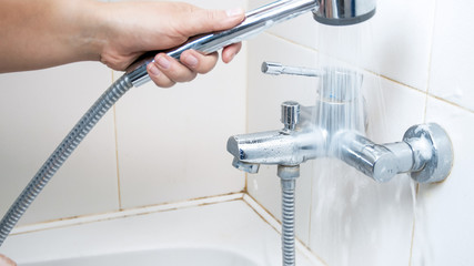 Closeup photo of young woman washing detergent suds from bathroom water tap