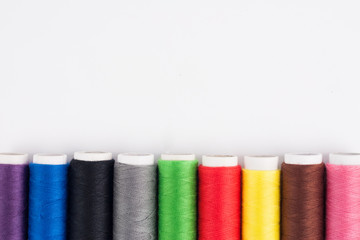 Row of bobbins of new colorful threads on white background. Top view