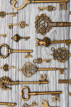 Many vintage keys on a light wooden background, vertical frame