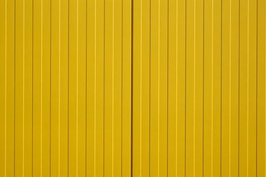 Leuchtend gelbe Blechfassade / Die Nahaufnahme einer farbintensiven und leuchtend gelben Wellblechwand eines Einkaufszentrums.