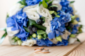 Details of the morning of the wedding day. two gold wedding rings are on the brown wood table