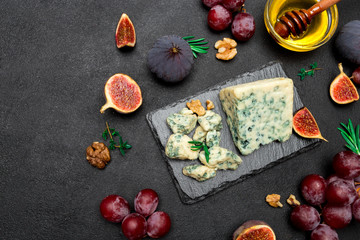 Slice of French Roquefort cheese and fruits on stone board