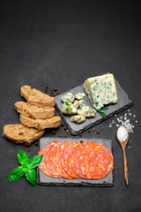 Slice of Roquefort cheese and chorizo sausage on stone serving board