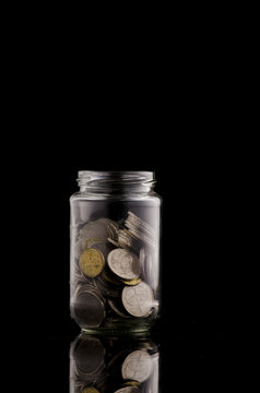 coin in transparent glass jar shot under low light for financial concept