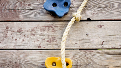 Closeup photo of rocks for climbing and rope on wooden wall at children playground