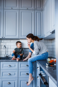 Mom And Son Are Sitting On The Table In The Kitchen