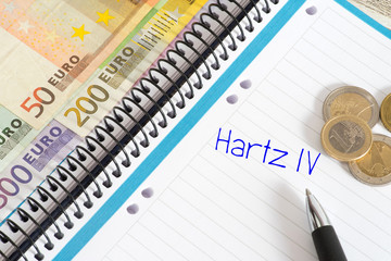 Euro Geldscheine und Münzen, ein Notizblock und Hartz 4